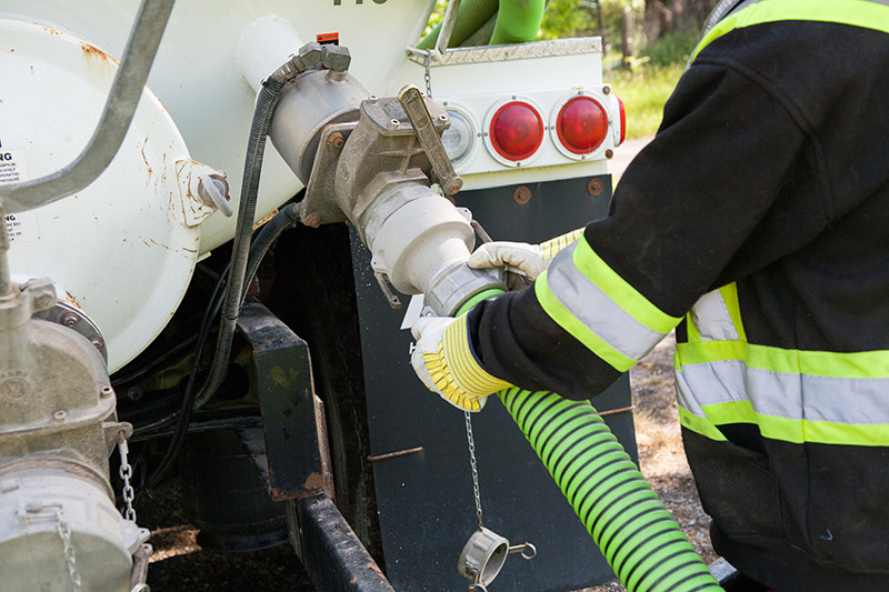 Man connecting hose to septic truck